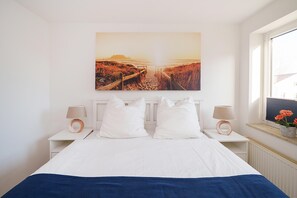 A bedroom with a bed, two bedside tables, a window with a view, and a wall-mounted picture. - Cozy vacation apartment with Wi-Fi & parking—just 450 m from the sandy beach (Bansin)