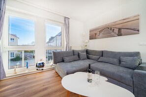A modern living room with a grey sofa, a white coffee table, and a painting on the wall. - Cozy vacation apartment with Wi-Fi & parking—just 450 m from the sandy beach (Bansin)