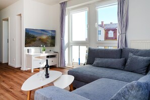 Ein modernes Wohnzimmer mit einem grauen Sofa, einem weißen Couchtisch und einem flachbildfernseher, der an der Wand befestigt ist.