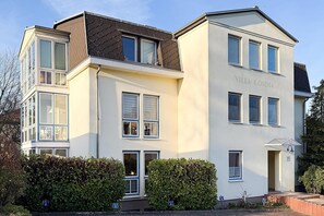 Ein mehrgeschossiges Gebäude mit moderner Architektur, das eine markante Eingangstür aus Glas und eine Schilder mit der Aufschrift 'VILLA COSIMA' zeigt.