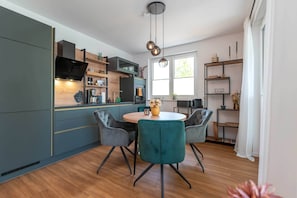 Une cuisine moderne avec un coin repas, un plancher en bois et une grande fenêtre.