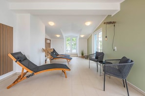 A sunlit room with three sun loungers, a wicker chair, and a large window. - "Haffhafen" Vacation Apartment with Sauna & Balcony on the Szczecin Lagoon in Zirchow (Zirchow)