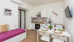 A compact apartment with a kitchenette, a dining area, and a bed. - Apartment 'Il Tulipano House' with Private Terrace, Wi-Fi and Air Conditioning (Catania)