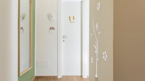 Un passadís amb una porta blanca, un mirall, una làmpada penjada a la paret i un adhesiu mural.