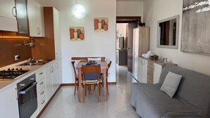 Una cucina moderna con zona pranzo, divano e televisore sullo sfondo.