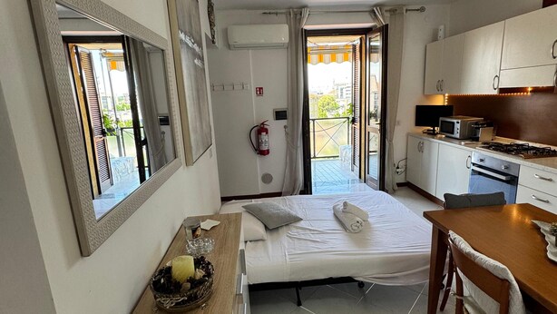 Una camera d'albergo compatta con un letto, angolo cottura, zona pranzo e bagno.