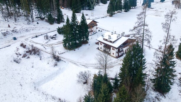 Un paisaje nevado con una casa grande rodeada de árboles.