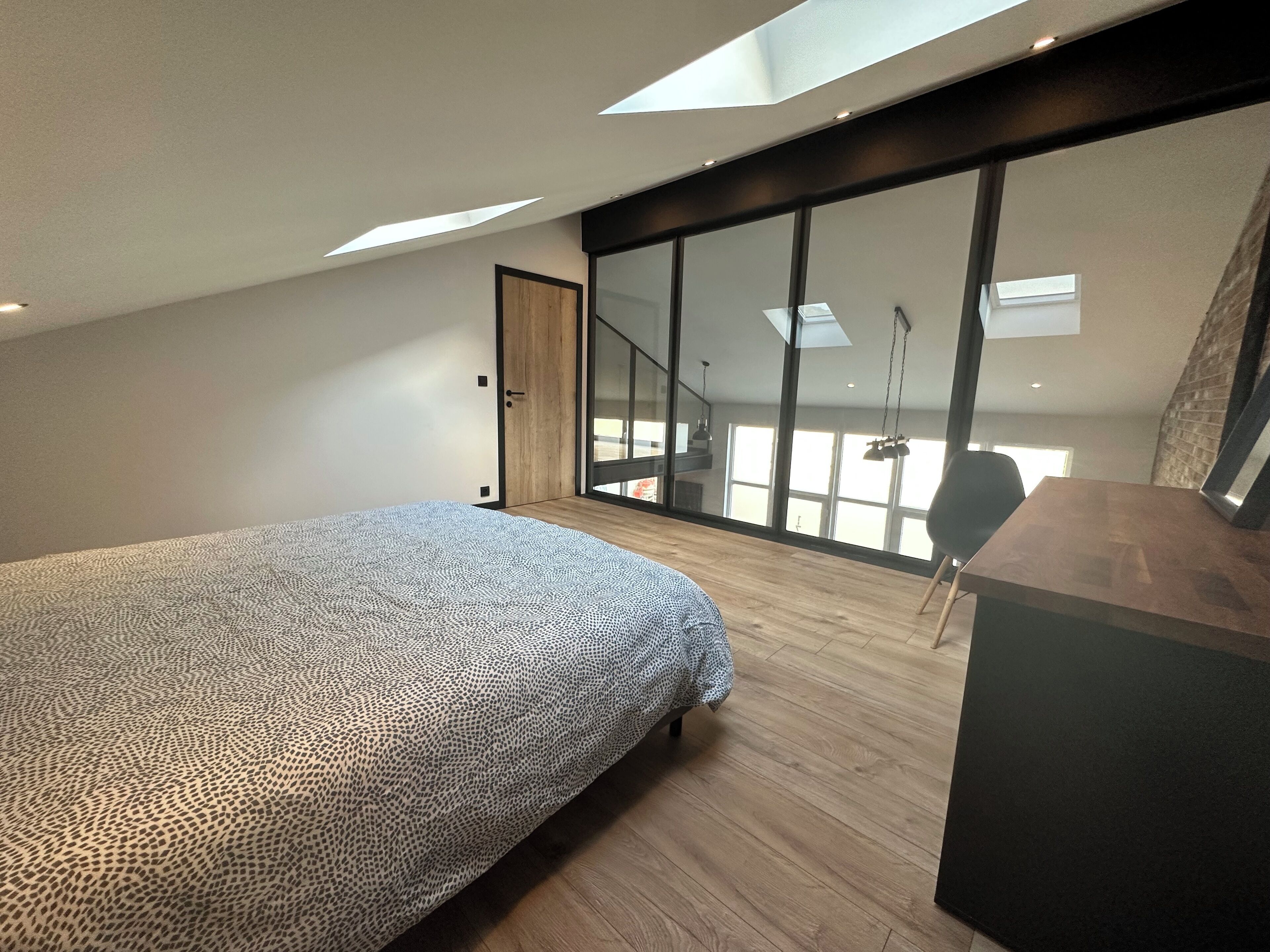 Ein modernes Schlafzimmer mit einem großen Bett, einem Schreibtisch und einem Oberlicht.