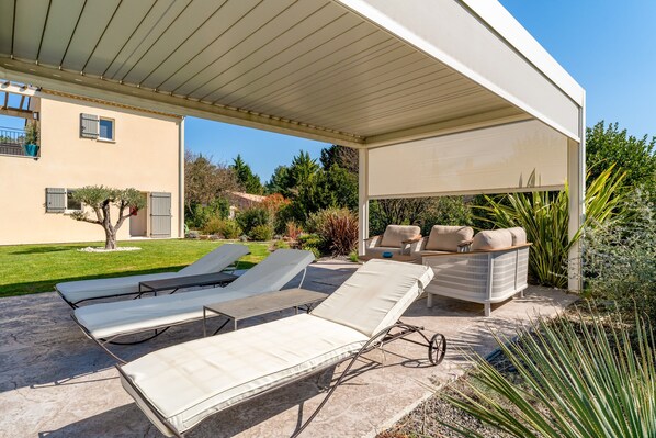 A covered outdoor patio with lounge chairs, a sofa, and a table.