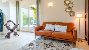A living room with a leather sofa, patterned rug, and wall decor. - “Jamin” Room with Private Terrace, Wi-Fi, and Air Conditioning (Fontarèches)