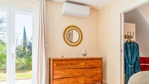 Una habitación con un aparador de madera, un espejo, una bata y una puerta que da a un jardín.