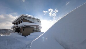 Un edificio de varios pisos con balcones cubiertos de nieve y un cielo despejado.
