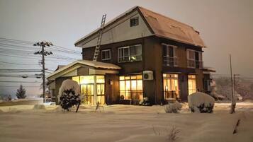 A two-story house with a sloped roof, large windows, and a visible chimney.