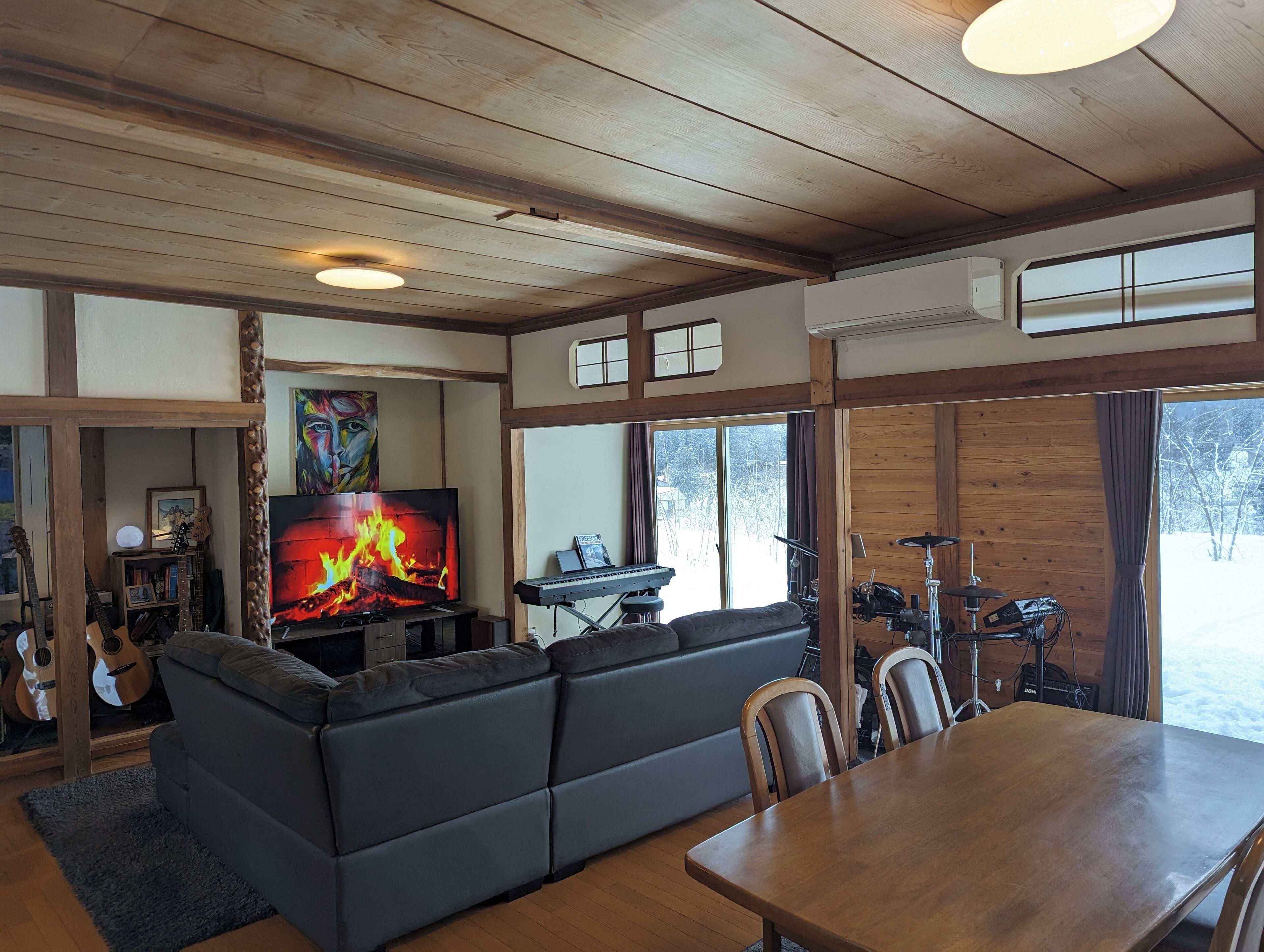 A cozy living room with a fireplace, a sofa, a dining table, and a view of the outdoors.