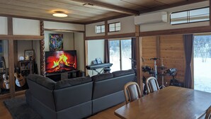 Una sala de estar acogedora con chimenea, un sofá, una mesa de comedor y vistas al exterior.