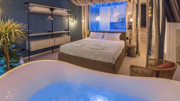 A modern bedroom with a large bed, a built-in bathtub, and a view of the city. - Welcome to Blue Perlage, your oasis of luxury and relaxation, nestled in the heart of Vernazza, one of the pearls of the Cinque Terre.Blue Perlage is not just a place to sleep but a true sensory experience.The sophisticated and modern design of the inter (Vernazza)