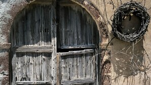 An old stone building with a large wooden door and a small window. - Kamari Real Living, with Caldera views and Jacuzzi (Manolas)