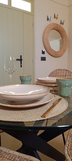 A dining table set with plates, a glass, and a woven placemat. - Kamari Real Living, with Caldera views and Jacuzzi (Manolas)