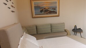 A hotel room with a bed, a sofa, a small table, and a painting on the wall. - Kamari Real Living, with Caldera views and Jacuzzi (Manolas)