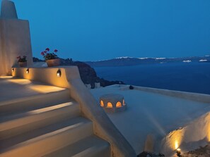A set of white stone steps leading to a terrace with potted plants and lights, overlooking a coastal landscape with a view of the sea and distant mountains. - Kamari Real Living, with Caldera views and Jacuzzi (Manolas)