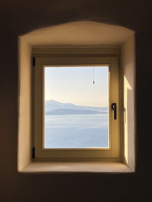 A window with a view of a body of water and distant mountains. - Kamari Real Living, with Caldera views and Jacuzzi (Manolas)
