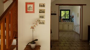 A staircase leading to a kitchen with a window, a potted orchid, and framed pictures on the wall. - Charming house with shared pool in Contres (Contres)