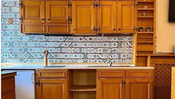Una cocina con armarios de madera, salpicadero de azulejos y un refrigerador.