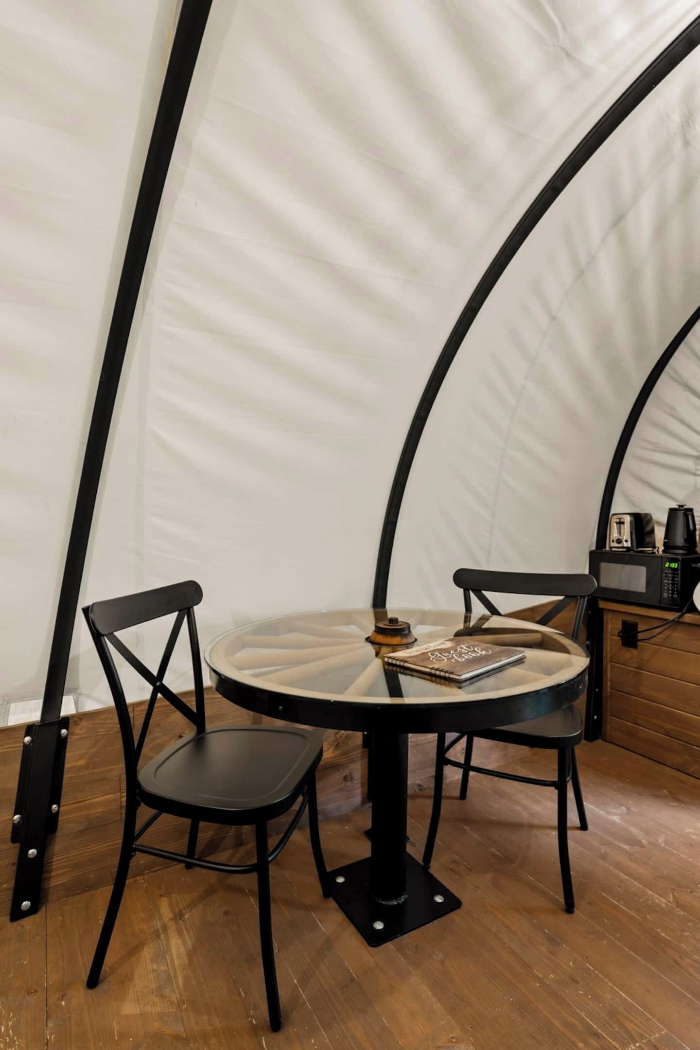A round table with two chairs in a tent-like room with wooden flooring.
