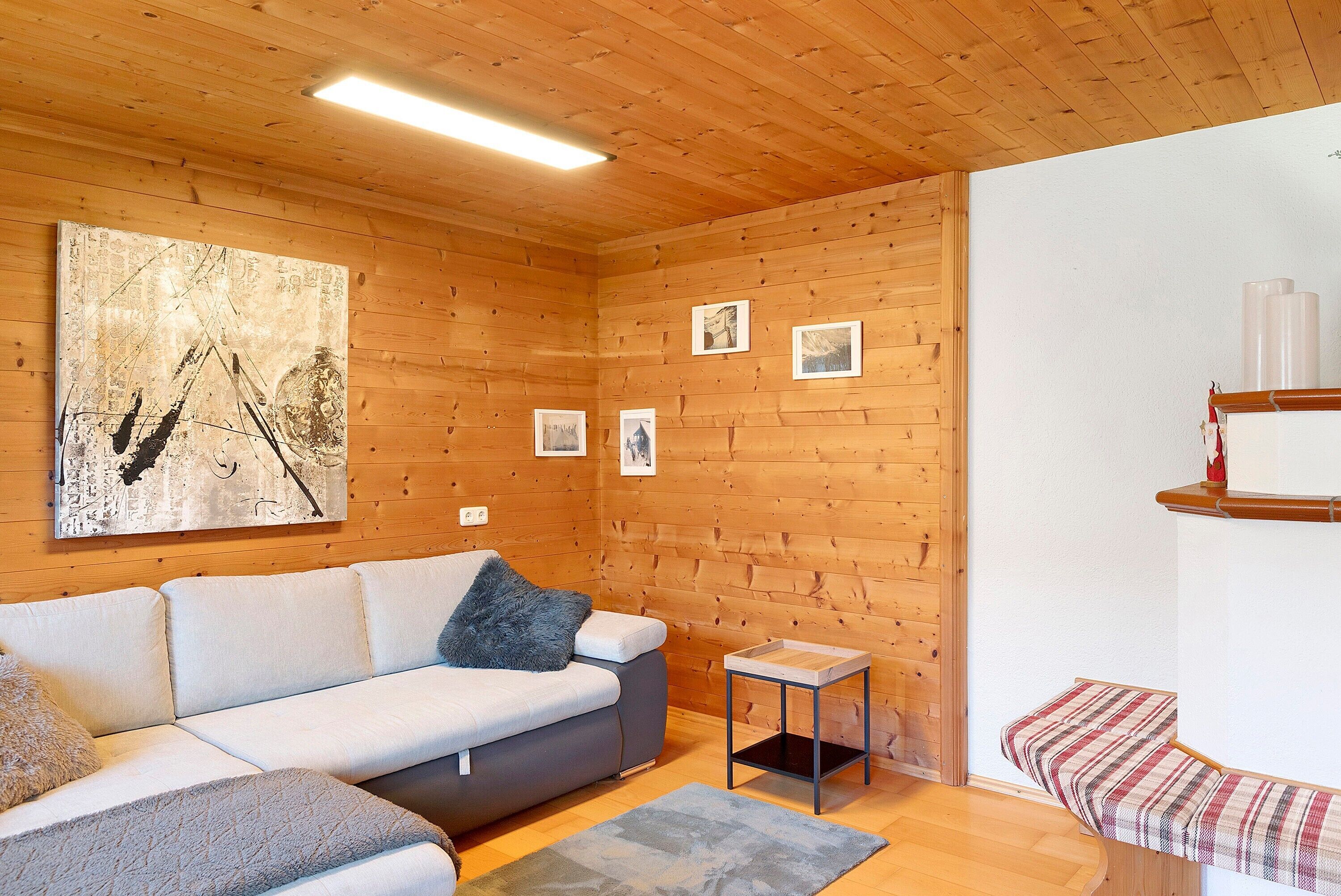 A wooden-paneled room with a sofa, a small table, and a bench.