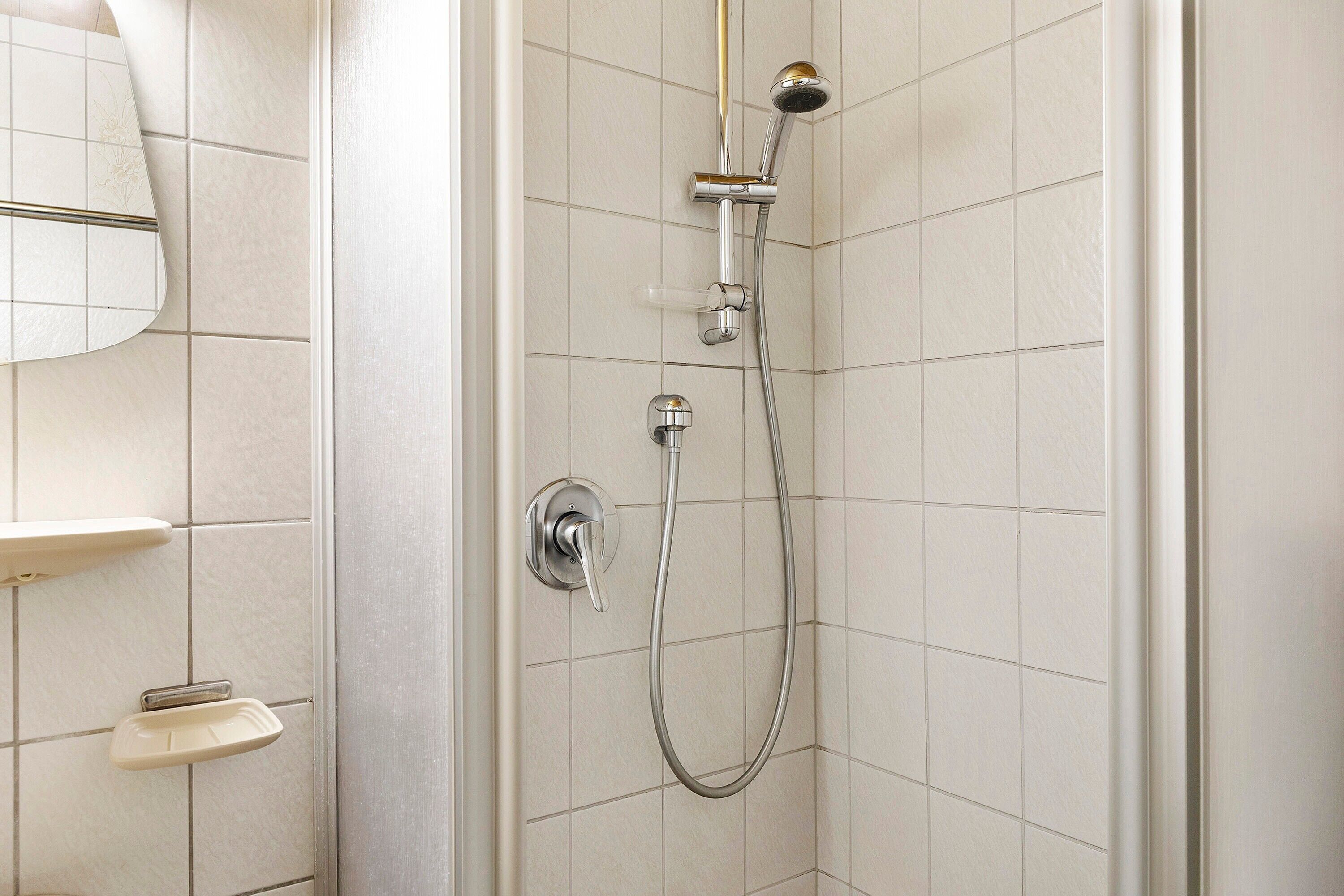 Eine Dusche mit Duschbrause und Wandarmatur.