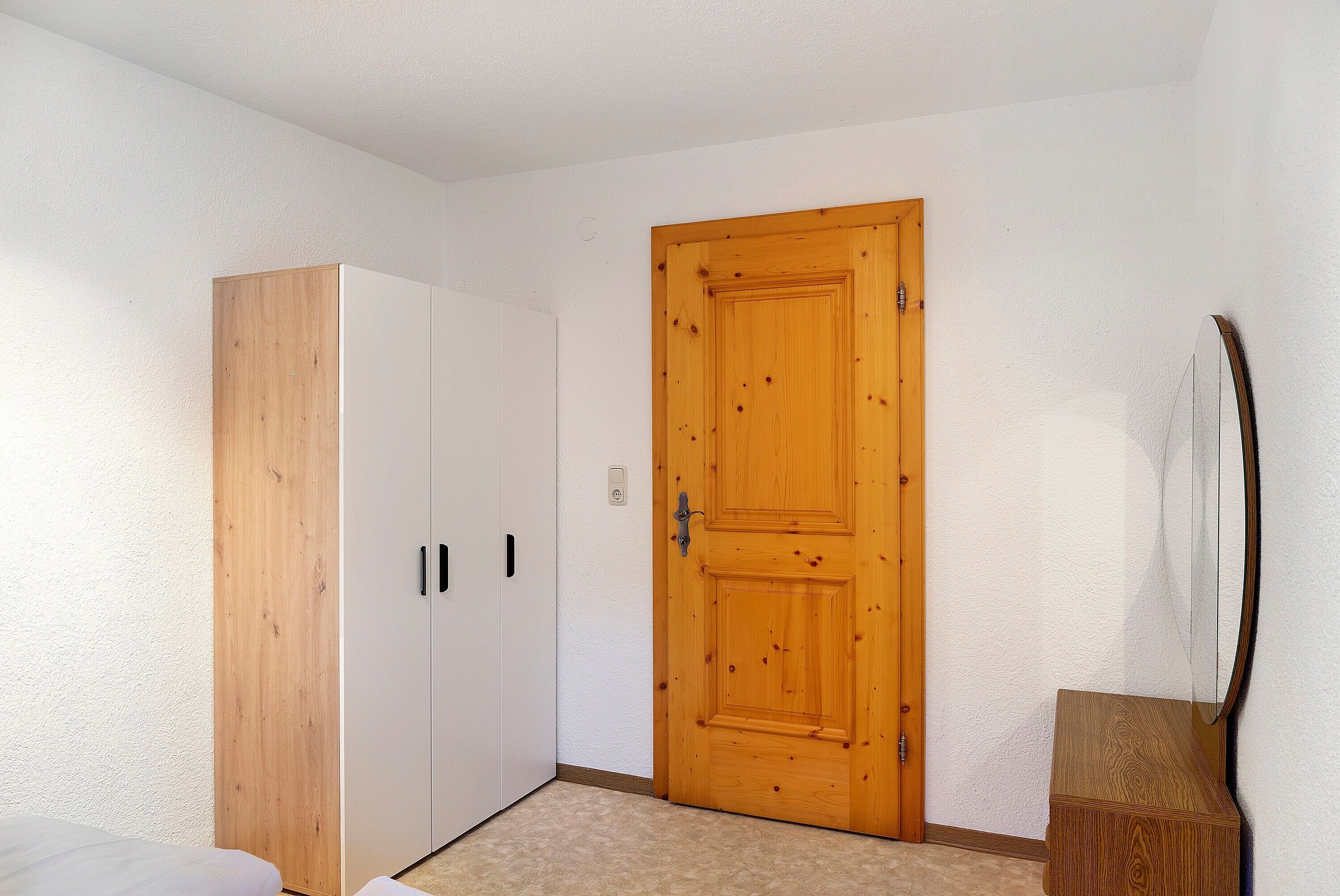 Ein Schlafzimmer mit einem Holzschrank, einer Holztür und einem kleinen Nachttisch.