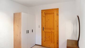 Ein Schlafzimmer mit einem Holzschrank, einer Holztür und einem kleinen Nachttisch.