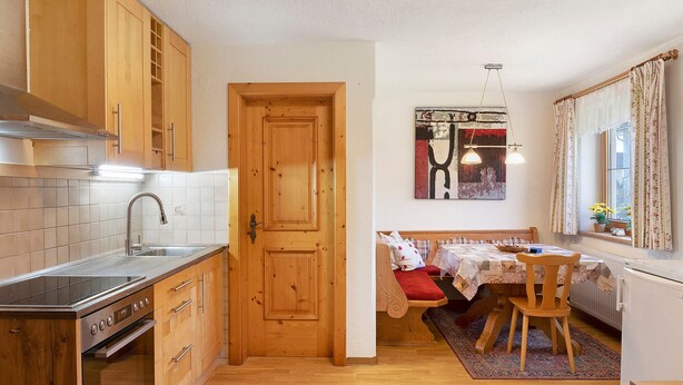 Une cuisine compacte avec des meubles en bois, une cuisinière encastrée et un coin repas comprenant un banc et une table.