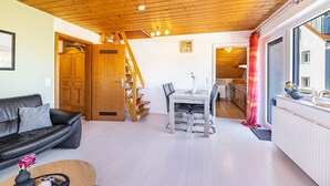 A wooden ceiling, a dining area with chairs and a table, a black leather sofa, and a wooden door. - Apartment "Sonnenblick" with Balcony and Wi-Fi (Albstadt)