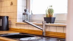 A kitchen with a double sink, a potted plant, and a window with natural light. - Apartment "Sonnenblick" with Balcony and Wi-Fi (Albstadt)