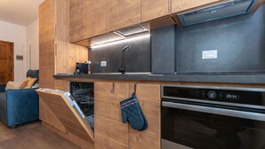 A modern kitchen with wooden cabinetry, a dishwasher, an oven, and a coffee maker. - El Mugo-Boscoverde 1 (Rocca Pietore)