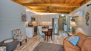 A compact kitchen with a wooden ceiling, a dining area with a table and chairs, a sofa, and a small rug. - Keys to the Sea + Cabana Club! (Key Colony Beach)