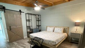 A bedroom with a bed, a nightstand, a hanging light, a ceiling fan, and a wardrobe. - Keys to the Sea + Cabana Club! (Key Colony Beach)