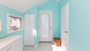 Una habitación con paredes verde azulado, puertas blancas y una ventana.