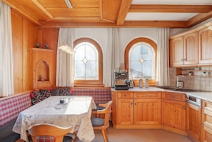Une cuisine chaleureuse avec des meubles de rangement en bois, une table à manger entourée de chaises et un banc.