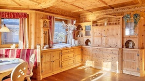 A wooden cabin interior with a dining area, wooden cabinets, and a large window. - Holiday Home 'Haus Hart Im Zillertal 6 People' with Mountain View, Terrace & Wi-Fi (Hart im Zillertal)