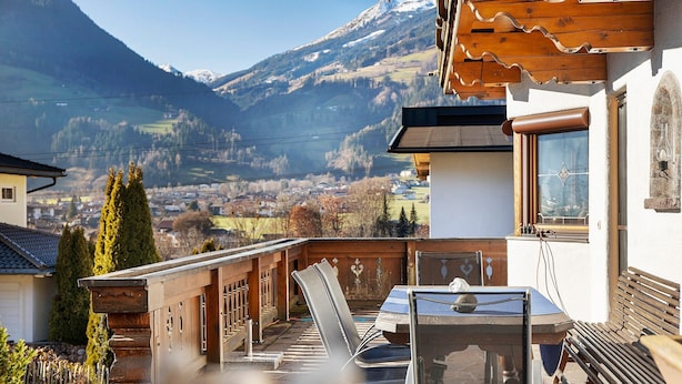 A chalet with a wooden deck, a table, and chairs, overlooking a valley and mountains. - Holiday Home 'Haus Hart Im Zillertal 6 People' with Mountain View, Terrace & Wi-Fi (Hart im Zillertal)