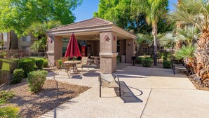A covered outdoor seating area with tables and chairs, surrounded by palm trees and a fence. - Cordillera Condo: Pools, Hot Tubs & Racquetball | Patio Retreat (Phoenix)