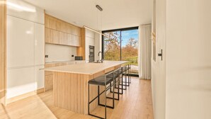 Una cucina moderna con un'isola grande, mobili in legno e vista sull'esterno.