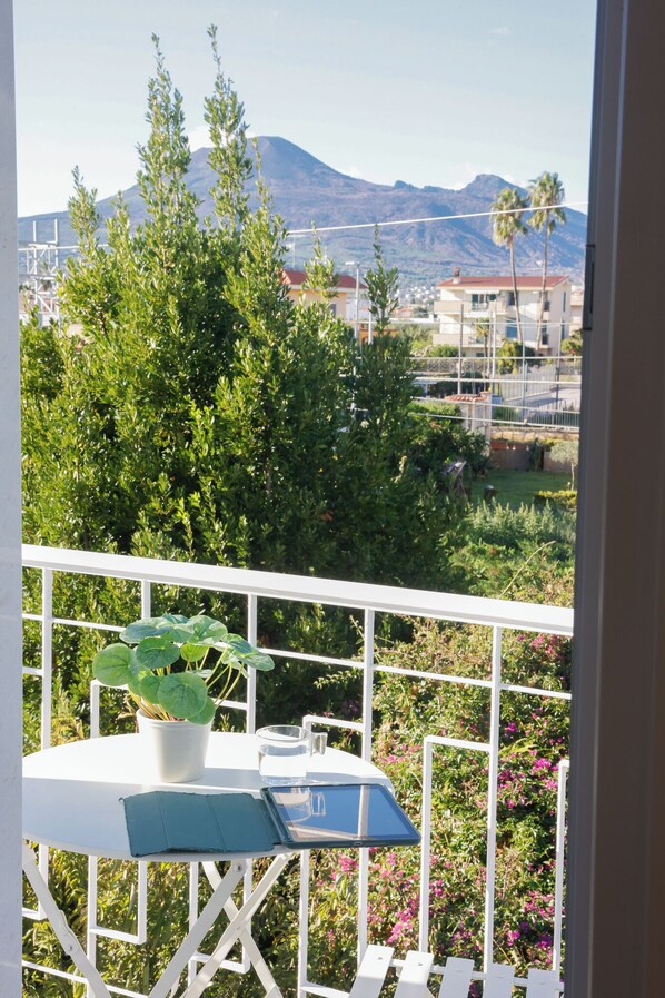A balcony with a table, potted plant, and a view of a mountain and buildings. - Sofia Suites &Rooms (Pompei)