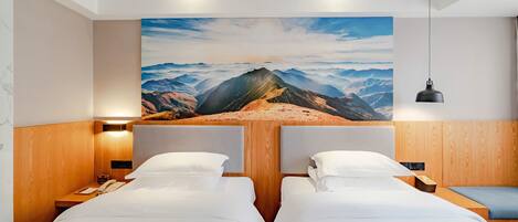 A hotel room with two beds, a large mountain view painting, wooden paneling, and a hanging pendant light.
