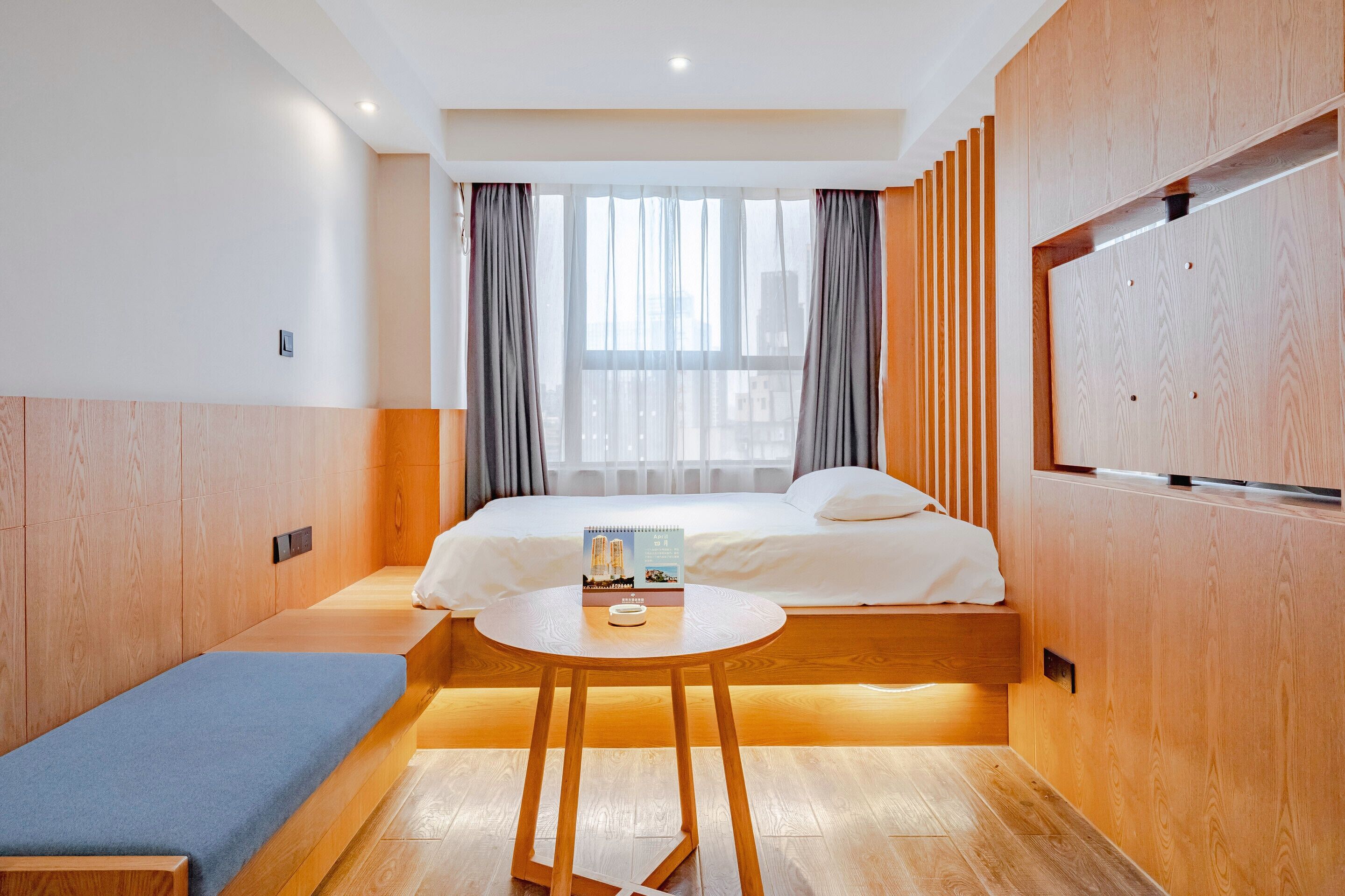 Ein modernes Hotelzimmer mit einem Bett, einem kleinen runden Tisch und einer Bank.