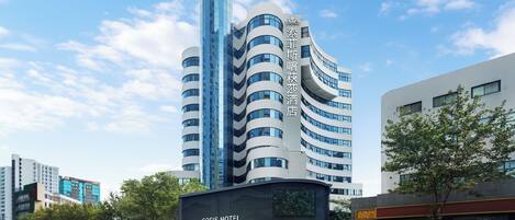 A modern hotel with a curved facade, multiple balconies, and a prominent entrance.