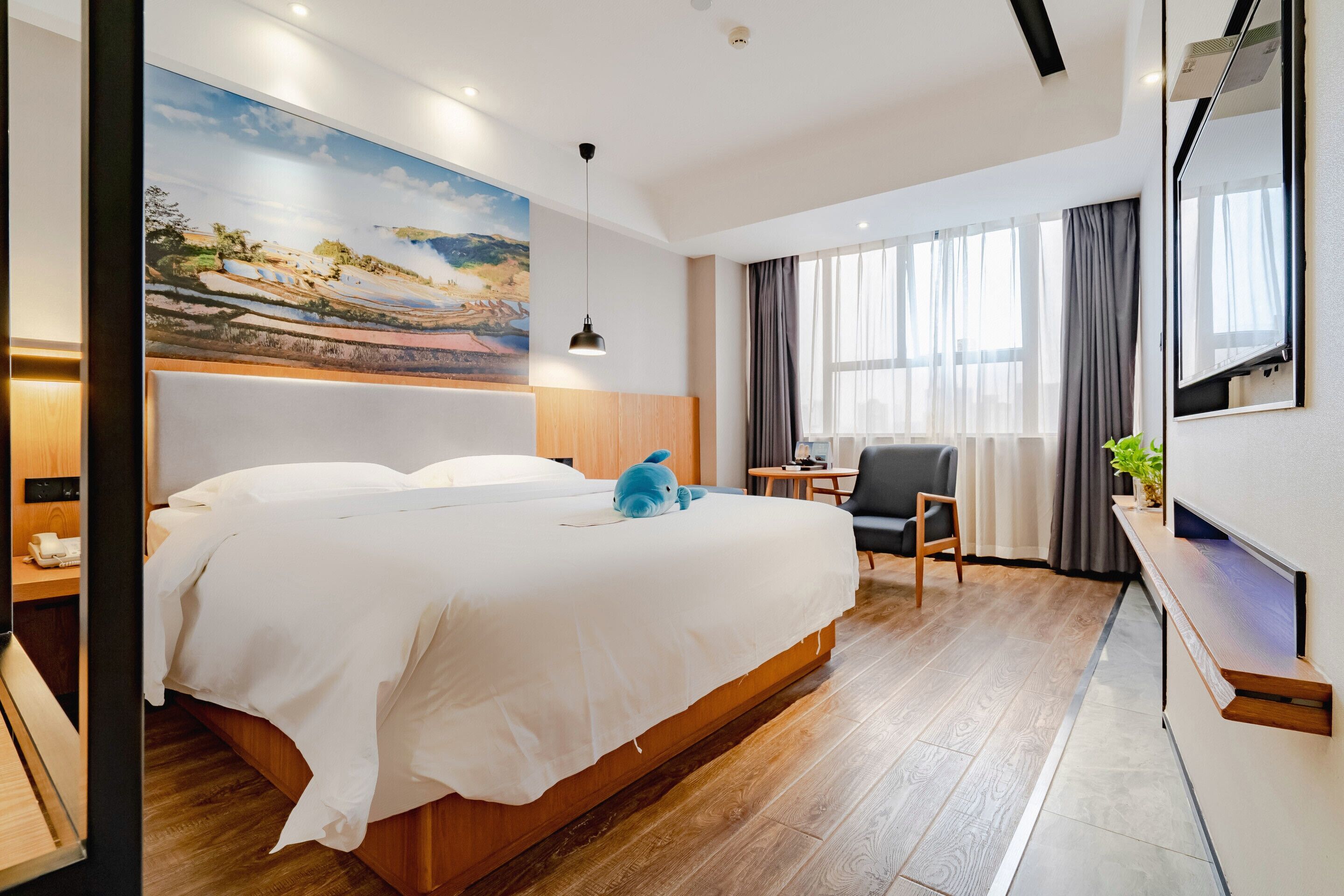A hotel room with a large bed, a desk, a chair, a TV, and a painting on the wall.