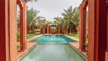 A pool area with a clear view of the water, surrounded by palm trees and red pillars.